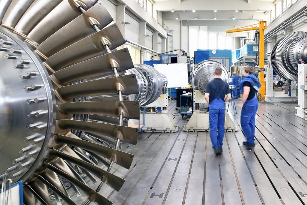 Zwei Mitarbeiter*innen eines Maschinenbauunternehmens untersuchen eine Turbine