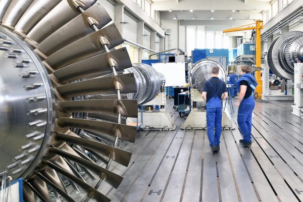 Zwei Mitarbeiter*innen eines Maschinenbauunternehmens untersuchen eine Turbine